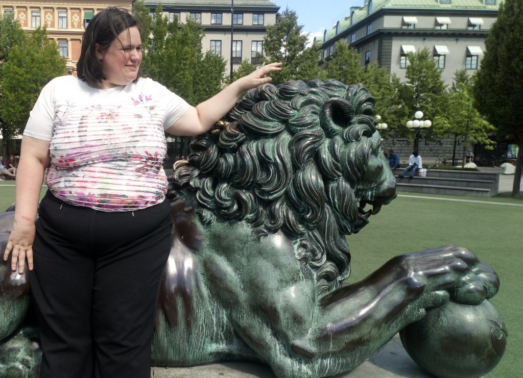 Sarah with her hand on a copper lion